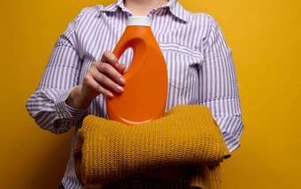 女人白色条纹衬衫持有橙色塑料瓶液体洗过来这里针织毛衣洗衣家庭家务清洁洗项目
