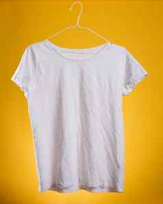 白色棉花皱巴巴的t恤挂悬挂器黄色的背景夏天衣服