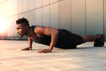 非洲男人。体育服装保持板材位置海滩锻炼在户外日落日出