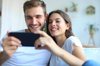 年轻的夫妇看在线内容聪明的电话坐着沙发首页生活房间