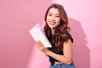 图像微笑年轻的女人摆姿势孤立的粉红色的背景墙持有书阅读