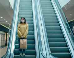年轻的女人保护面具移动购物中心