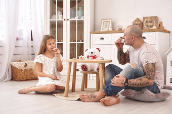 可爱的女儿穿白色衣服呵呵爱的父亲喝茶玩具菜现代儿童房间快乐家庭