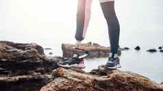 强大的身体裁剪图像禁用年轻的女人运动服装仿生腿站石头前面海