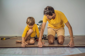 <strong>父亲</strong>儿子安装木层压板地板温暖的电影地板上红外地板上加热系统层压板地板上