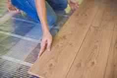 男人。安装木层压板地板红外地板上加热系统层压板地板上