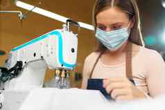 年轻的高加索人女人裁缝工作缝纫工厂穿保护医疗面具