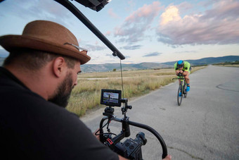 电视录像制作人采取行动拍摄三项全能运动运动员骑自行车