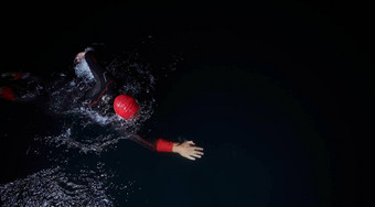 三项全能运动运动员游泳黑暗晚上穿潜水服