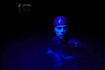 真实的铁人三项选手游泳运动员打破硬培训晚上霓虹灯过来这里光
