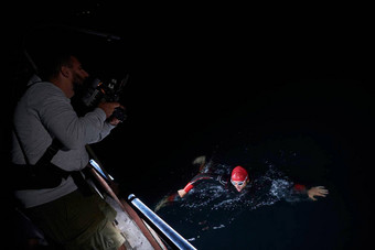 电视录像制作人采取行动拍摄三项全能运动游泳运动员晚上