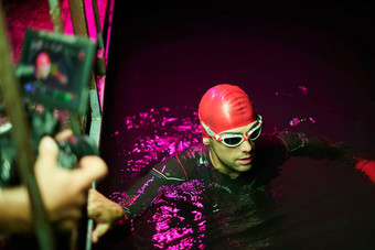 电视录像制作人采取行动拍摄三项全能运动<strong>游泳</strong>运动员晚上