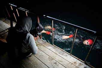 电视录像制作人采取行动拍摄三项全能运动<strong>游泳</strong>运动员晚上