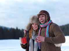 快乐年轻的夫妇喝温暖的茶冬天