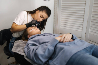 美容师使睫毛纹理程序年轻的模型现代睫毛护理程序层压扩展睫毛专业美工作室