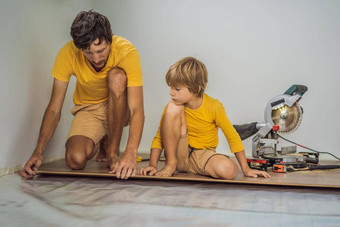 父亲儿子安装木层压板地板温暖的电影地板上红外地板上加热系统层压板地板上