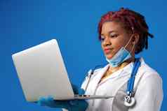 年轻的非洲美国女人医生移动PC蓝色的背景
