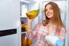 肖像年轻的金发女郎女人采取食物冰箱