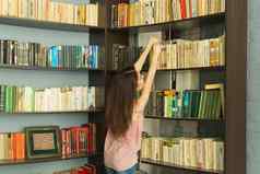 阅读图书馆人概念女孩达到书书架上微笑