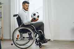 年轻的男人。轮椅持有足球球