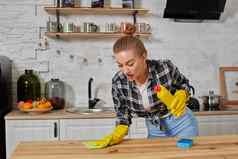 年轻的女人家庭主妇橡胶手套擦拭表格超细纤维布首页厨房
