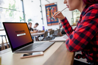一边视图年轻的女人坐着咖啡馆手打字移动PC电脑密码登录屏幕