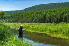 渔夫站河捕获鱼木钓鱼杆钓鱼工艺西伯利亚钓鱼杆树干年轻的树