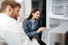 年轻的夫妇选择冰箱家庭设备商店