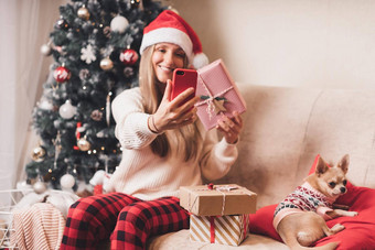 年轻的女人狗毛衣需要自拍肖像智能手机冬天假期享受圣诞节<strong>时间</strong>首页包装礼物<strong>视频</strong>闲谈，聊天移动电话