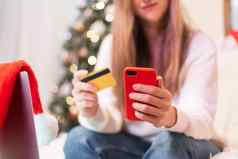 关闭女人移动电话信贷卡移动PC在线购物圣诞节假期女孩发短信消息首页快乐圣诞节快乐一年圣诞节树