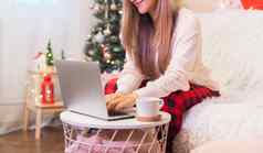 女人咖啡杯子打字移动PC视频闲谈，聊天在线购物圣诞节假期自由女孩沃金首页圣诞节树装饰