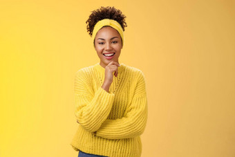 <strong>感兴趣</strong>兴奋热情的好看的女企业家时尚的毛衣头巾非洲式发型发型触碰下巴深思熟虑的微笑喜欢项目的想法站黄色的背景<strong>感兴趣</strong>