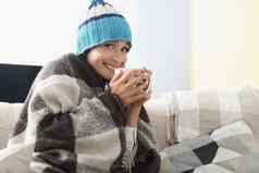 生病的女人杯热茶喝覆盖温暖的毯子