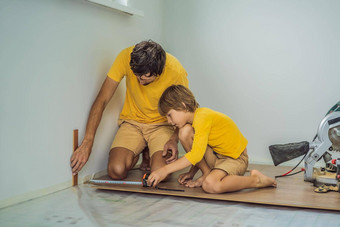 父亲儿子安装木层压板地板温暖的电影地板上红外地板上加热系统层压板地板上
