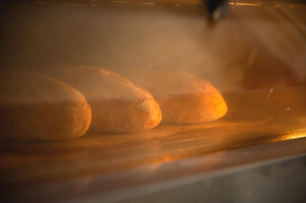 批处理新鲜的面包烘焙烤箱查看玻璃通过反射烹饪食物概念