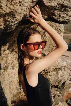 女人黑色的泳衣太阳镜岩石摆姿势夏天奢侈品