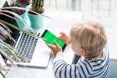 可爱的婴儿男孩看玩电话焦点色度绿色屏幕移动电话