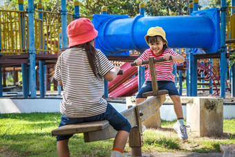 活跃的姐妹玩跷跷板户外操场上快乐孩子女孩微笑笑孩子们操场上玩学习童年