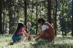 妈妈。女儿收集柴火引火物篝火野营的地方森林家庭孩子们使篝火自然森林家庭野营支出时间假期