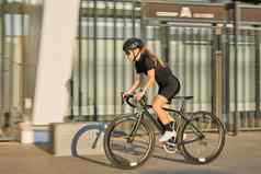 一边视图专业女骑自行车的人黑色的骑自行车服装保护齿轮骑自行车城市冲通过在户外阳光明媚的一天