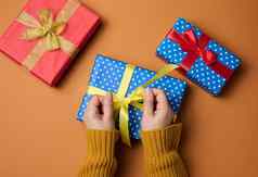 女手持有盒子包装礼物纸橙色背景圣诞节准备