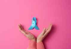 女人手持有光蓝色的丝带意识粉红色的背景男人的健康前列腺癌癌症意识运动概念