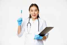 微笑亚洲女医生提高笔尤里卡手势持有剪贴板站医疗统一的白色背景