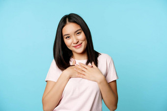 微笑亚洲女模型持有手心珍惜smth感觉护理温暖的爱感情站t恤蓝色的背景