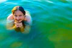 高加索人男人。浮动游泳湖蓝色的水