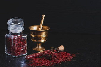 生有机红色的干藏红花香料木背景古董金属黄铜砂浆杵玻璃Jar管