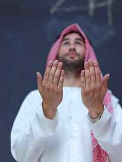 阿拉伯男人。使传统的祈祷神手祈祷手势前面黑色的黑板