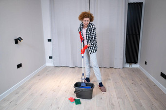 快乐的兴奋成熟的女人享受清洁房子跳舞洗地板上快乐上了年纪的女人享受清洁地板移动公寓做家务管家概念