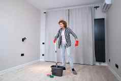 人做家务管家概念快乐高级女人保护手套清洗地板上舞蹈首页空公寓移动首页兴奋女人享受管家