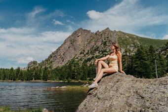 旅游女孩享受神奇的视图湖松柏科的森林神奇的视图坐着大石头海岸绿松石湖山徒步旅行自然公园可爱的女孩旅游坐着大石头湖水清晰的石头可见水